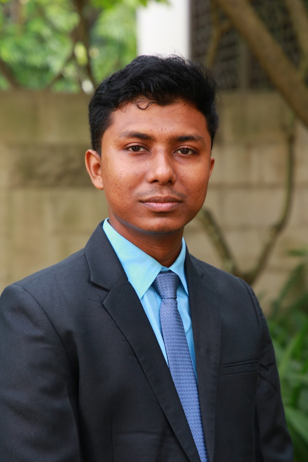 Abdul Barek wearing a dark suit and blue tie